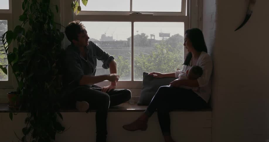A man and woman talk together by the window