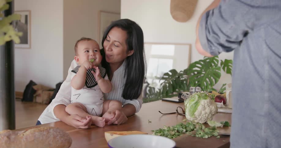 A woman kisses a baby and talks with a man
