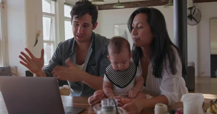 Two parents and a baby sit at the table together