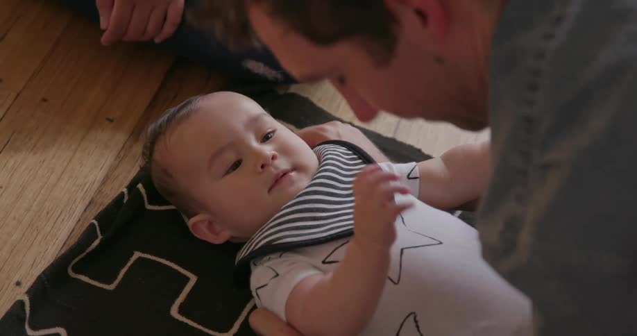 A man leans over talking to a baby