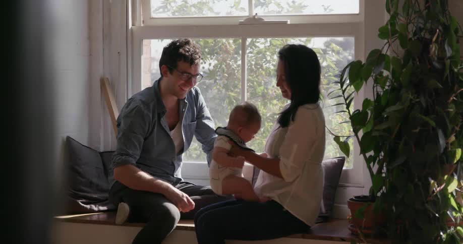 Parents sit on the window with their baby