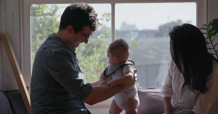 Man holds a baby while sitting in front of a window
