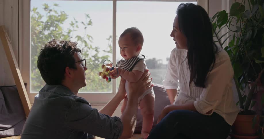 A mother and father are playing with a baby