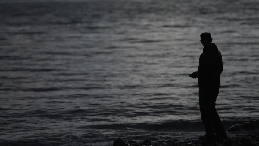 Man standing by body of water at dusk