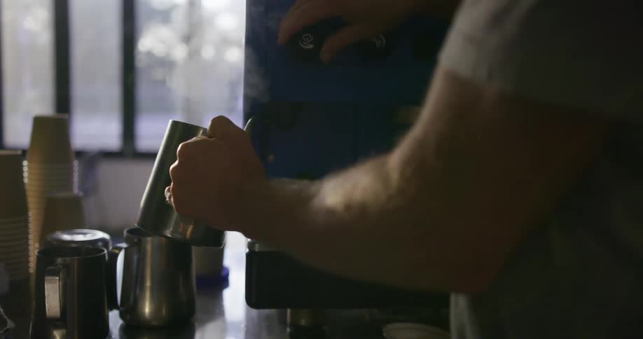 A man fills a mug with steaming coffee