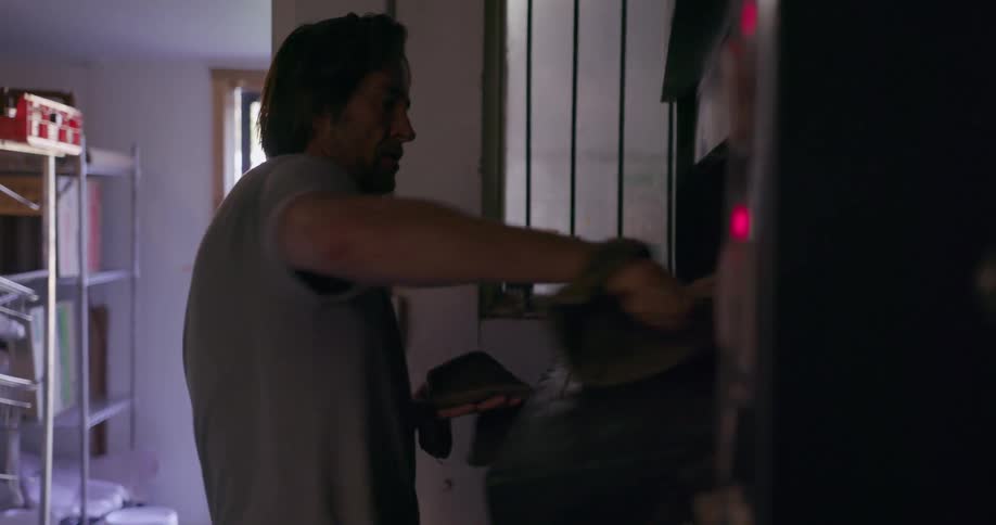 Man wearing oven mitts removes a pan from the oven
