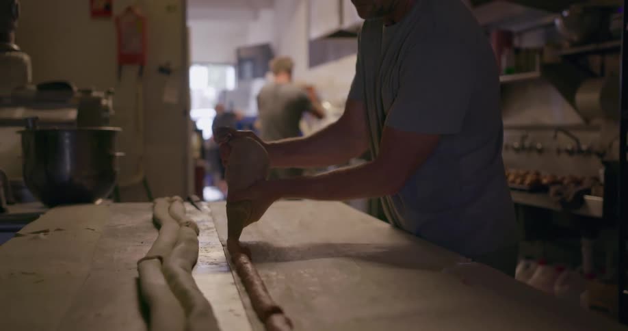 A man is working in the kitchen with some dough