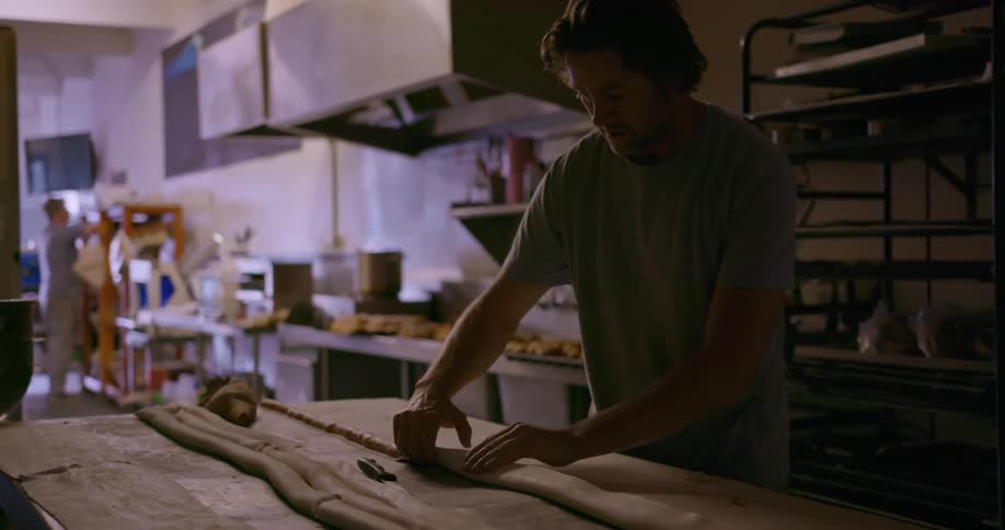 A man is shaping dough in a kitchen
