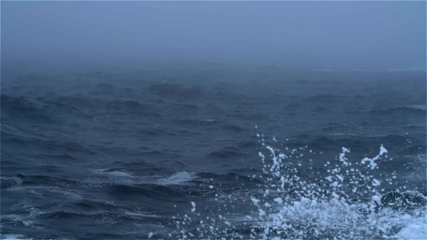A body of water is foggy and very rough waves move around