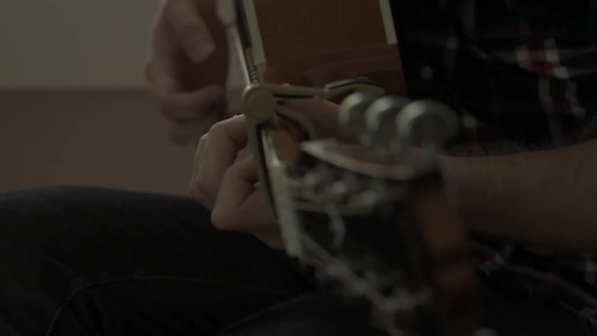 Close up of someone playing a guitar and making adjustments