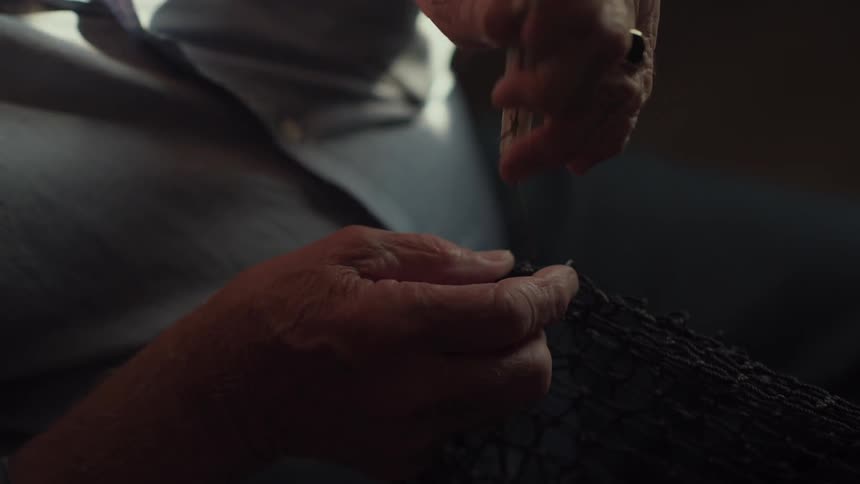 A man is knitting a net with a stick