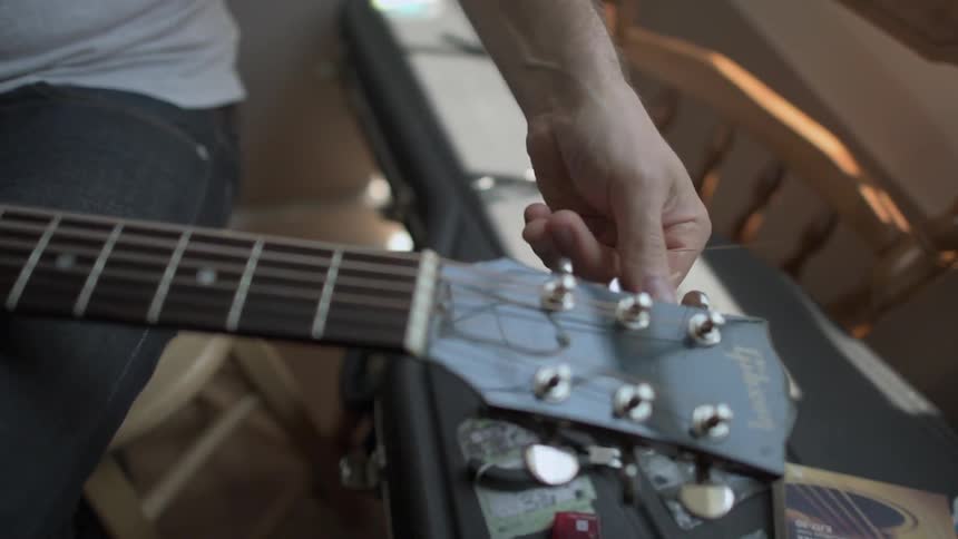 A person is adjusting his guitar