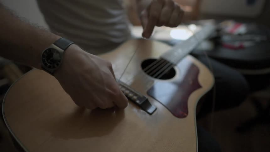 A person restrings a guitar