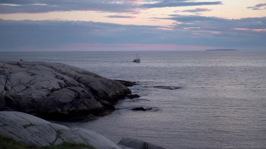 A boat floats on the ocean at sunset