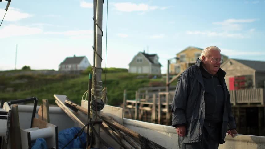 Man stands on a boat with houses in the background