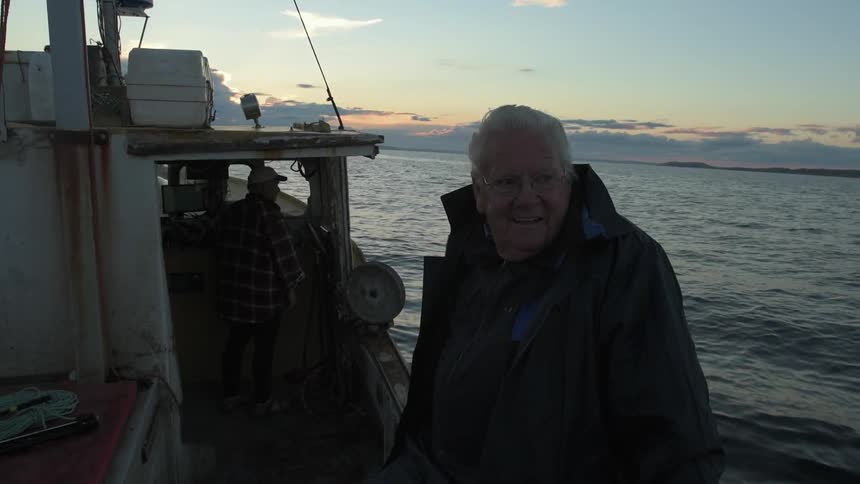 A man smiles as he looks around on his boat