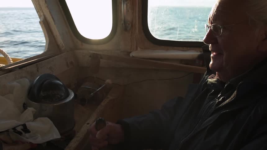 A man sits in a boat interior on a sunny day