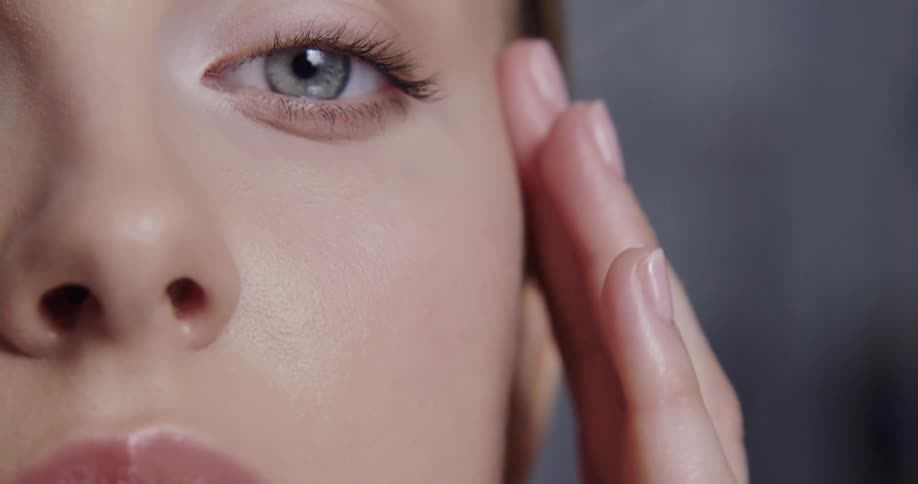 Close up view of a woman applying cosmetics to her face is displayed