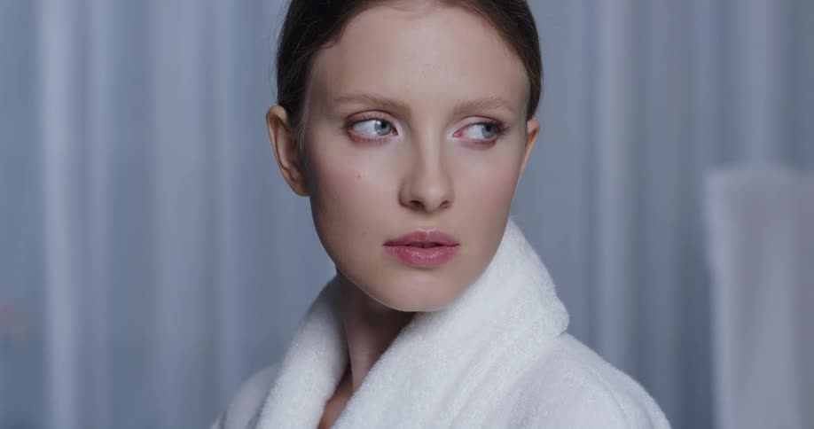 A model poses in light makeup and a white terrycloth robe