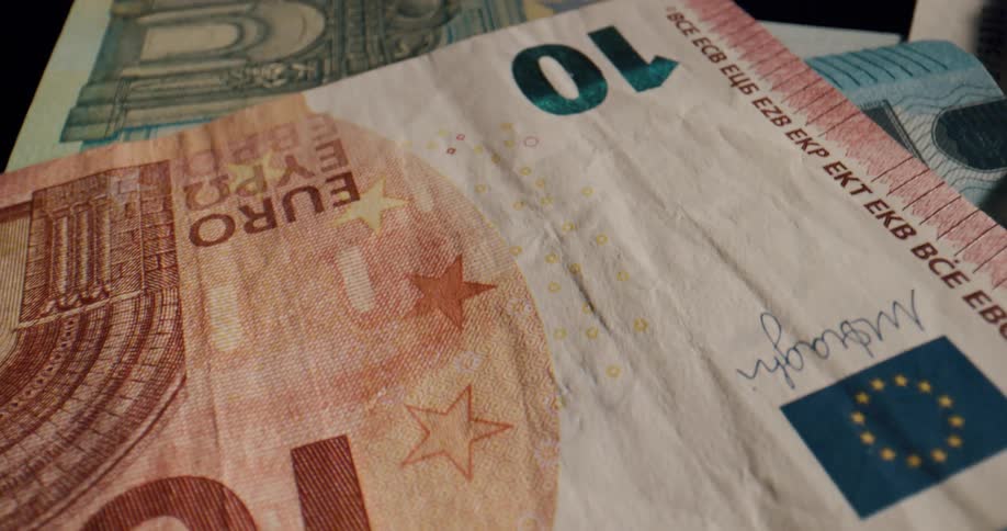 European banknotes are piled on a table one by one