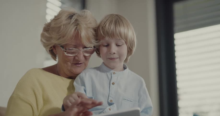 A grandmother and grandson use a tablet together