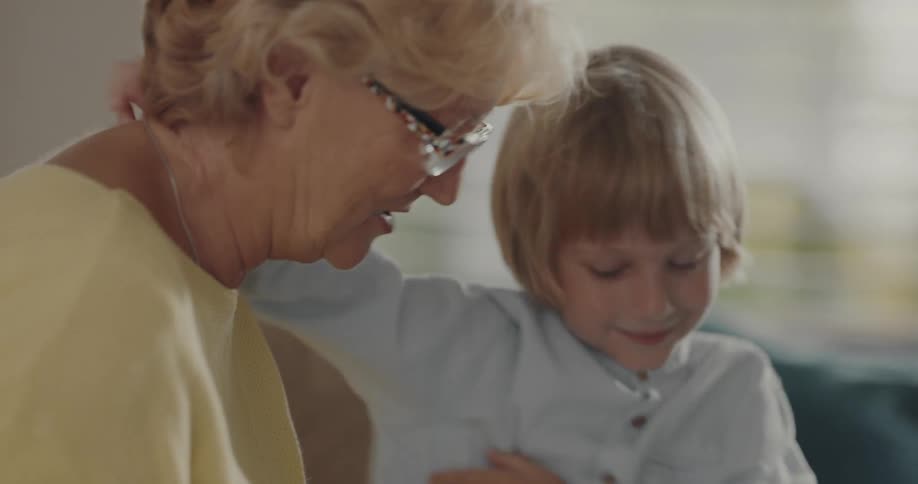 While sitting on a couch grandmother and daughter hug with a smile
