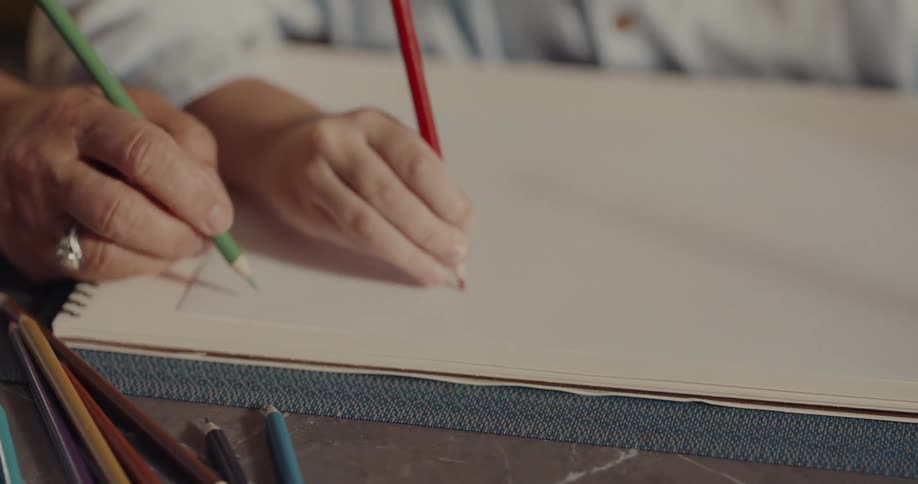 Elderly woman and child draw with colored pencils