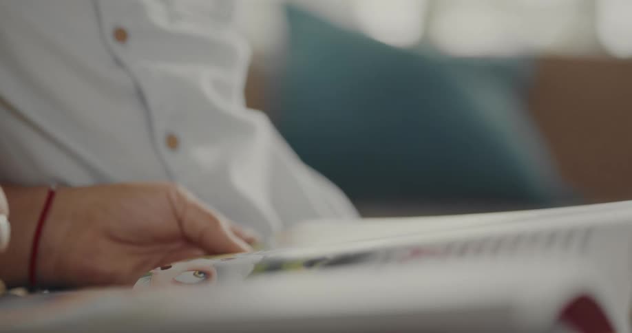 A child is reading a book indoors during the day time