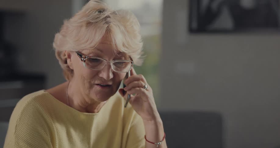 A woman smiles while talking on the phone at home