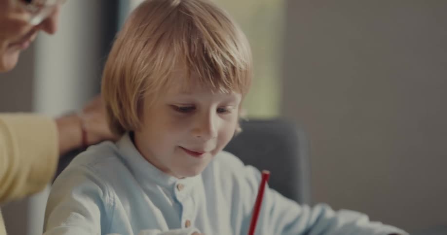Grandson and grandmother draw together in sketchbook using colored pencils