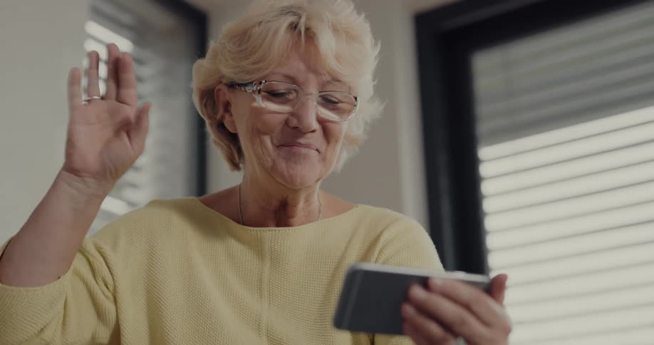 Older woman is waving and video chatting