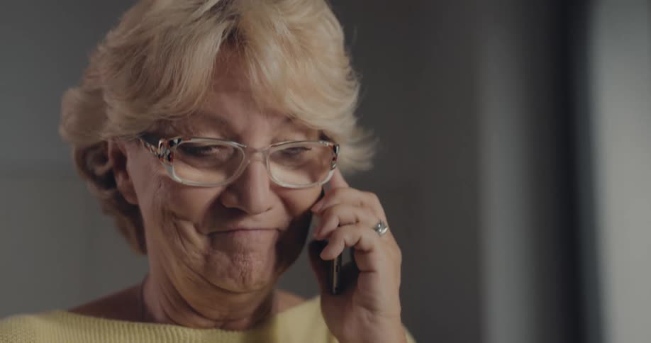 Elderly woman wearing a yellow shirt and talking on the phone
