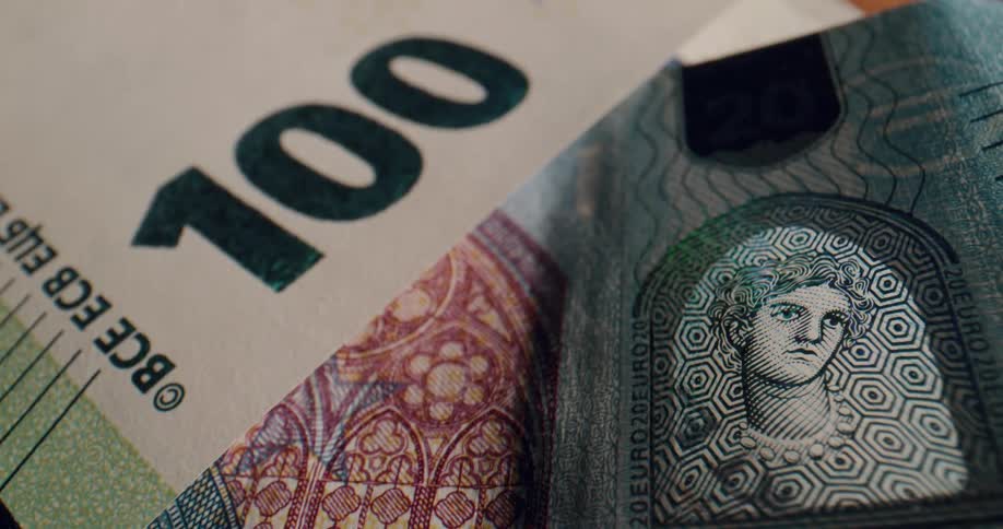 Currency bills decorated with geometric designs and artistic images lie scattered