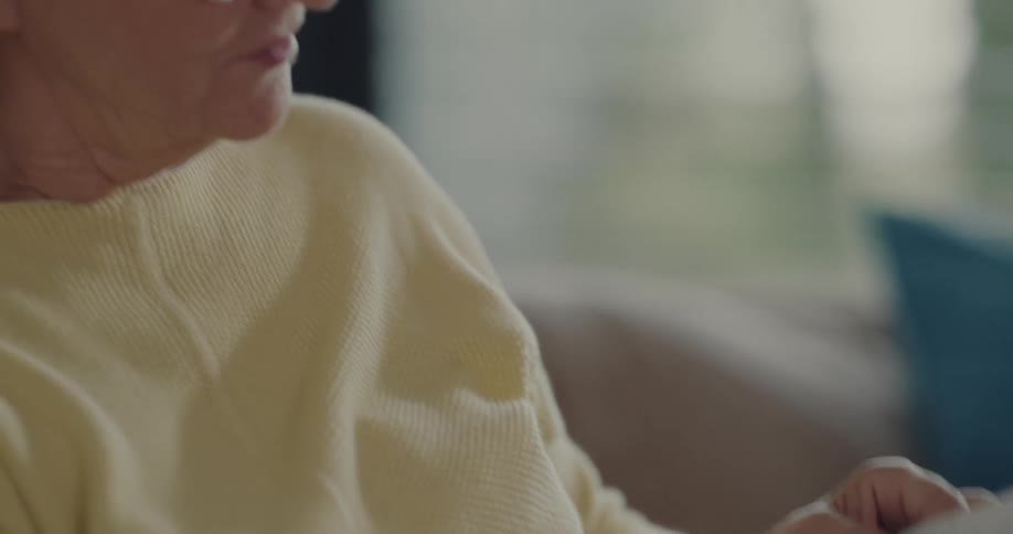 Female senior citizen reading a magazine in the living room at home
