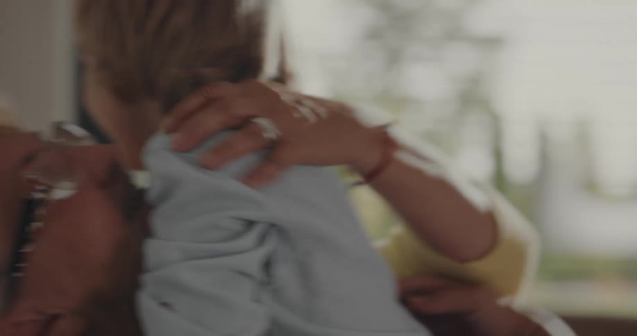 Happy grandmother sitting at home gives a hug and a kiss to her grandson