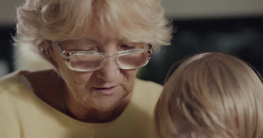 Grandma and grandson are drawing on paper indoors