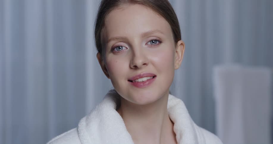 Close up of the face of a model wearing a white bath robe looking at the camera