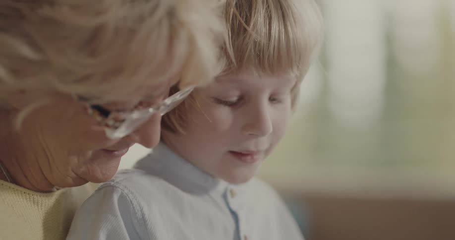 Grandmother and grandson sit playing tapping game on tablet