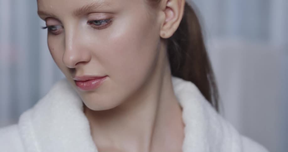 Female model with ponytail and white bathrobe looks sideways