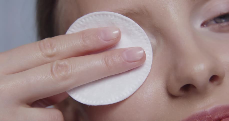 A woman smiles as she wipes her eye with a cotton round