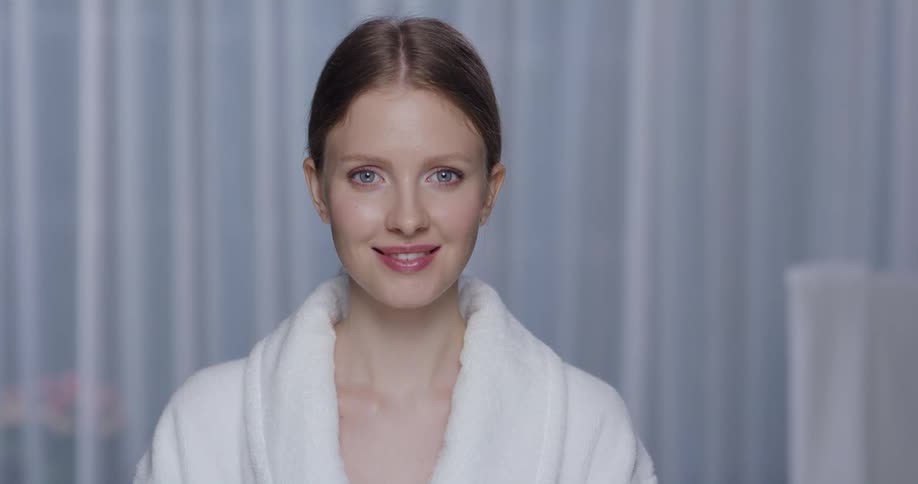 A woman wearing a bathrobe is looking forward and smiling