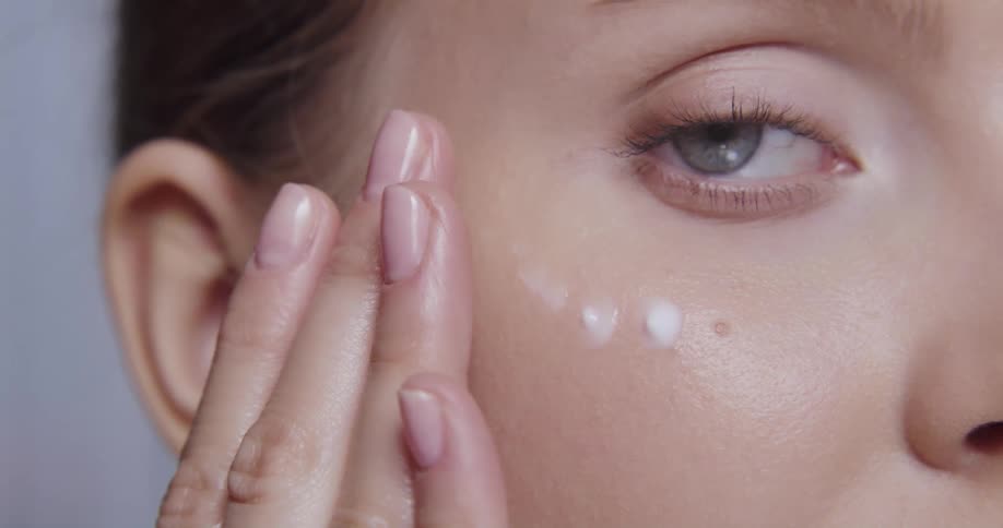 Close up view of a womans face while applying cosmetics