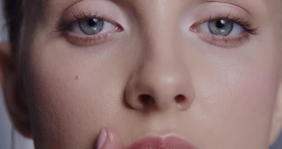 Woman wearing lipstick strokes hand along her face
