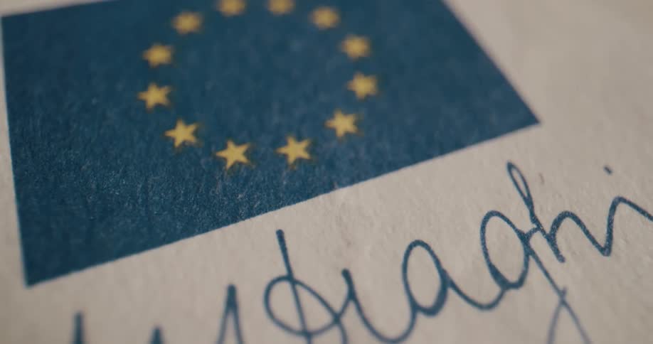 Close up of the european union flag over a signature on a piece of paper