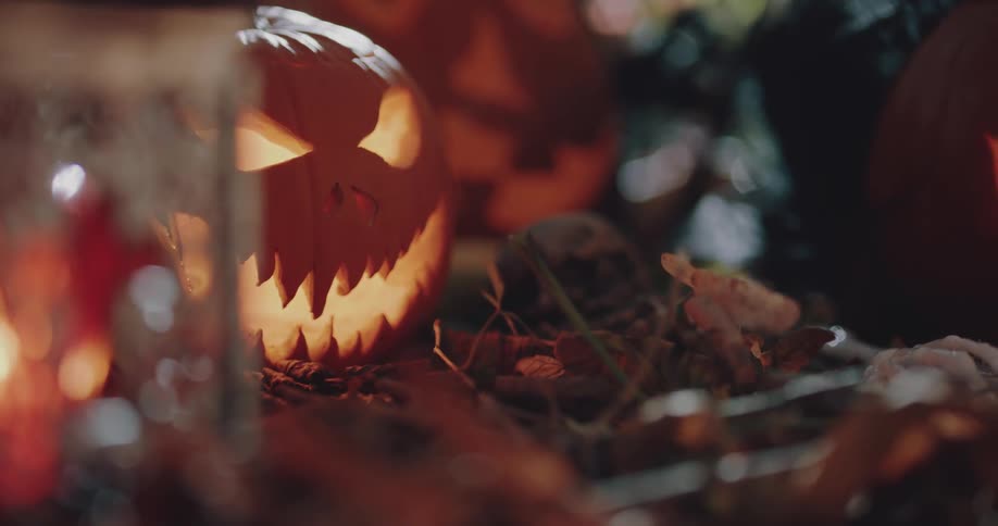 A carved pumpkin sits outside next to a burning candle