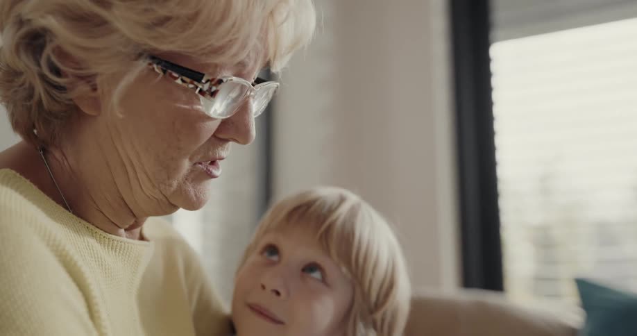 Grandma and grandson are reading a book together indoors