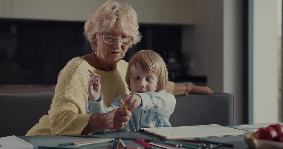 Grandmother and grandson are coloring together indoors