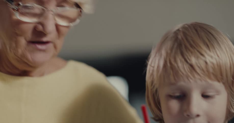Grandmother and grandson are drawing together indoors