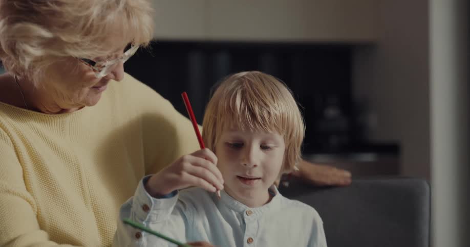 A woman draws with her grandson in the kitchen