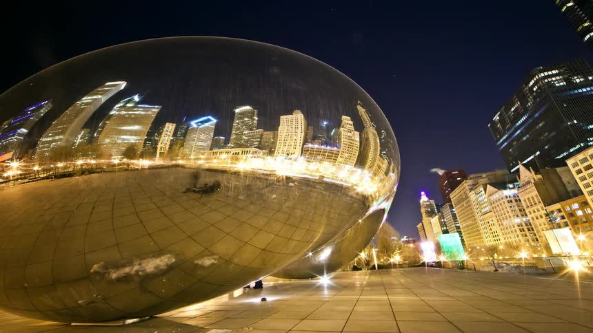 A large glove in a city court is reflecting the buildings at night in a time lapse